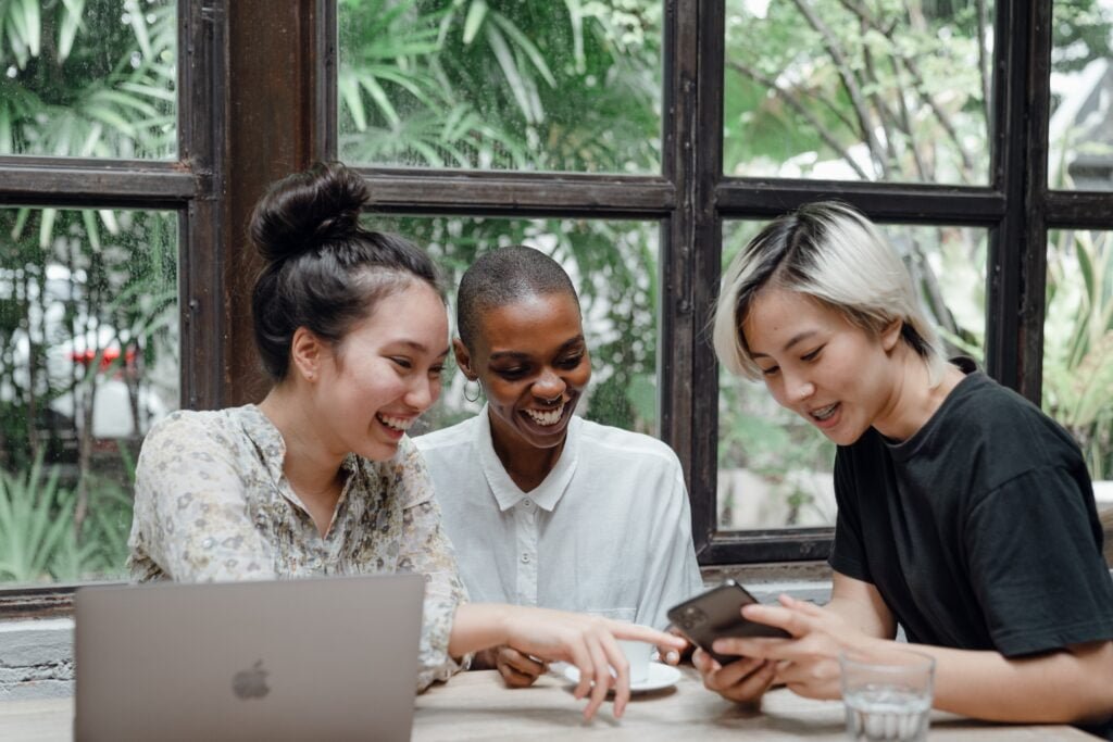 Mujeres conversando y revisando sus dispositivos digitales.